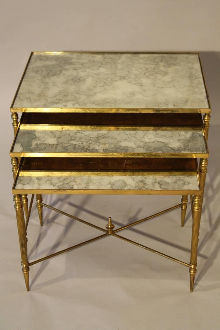 Nest of gilt metal and aged mirror plate side tables