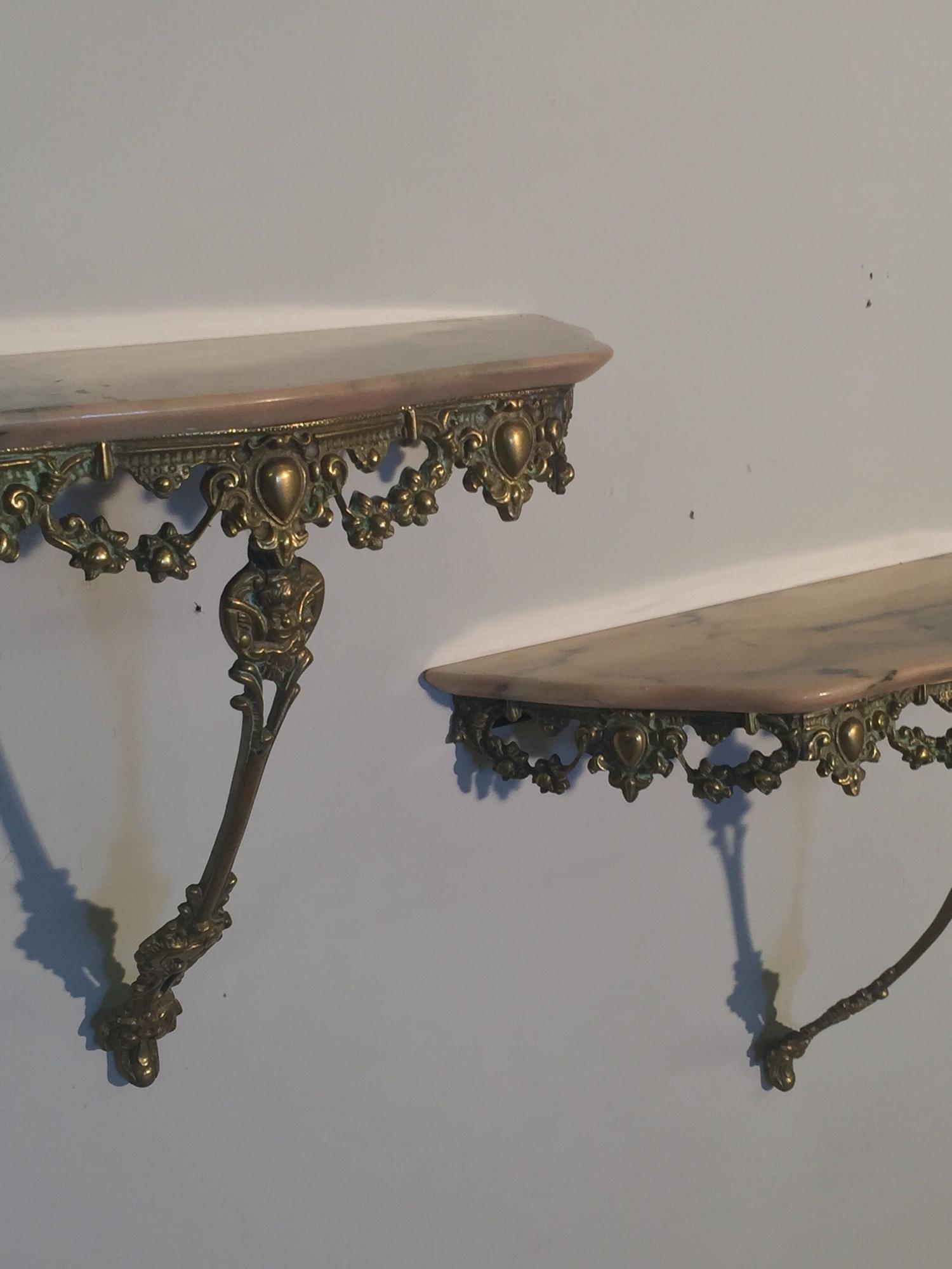 A pair of brass metal and pink marble consoles